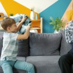 Grandfather old man is playing with joyful kid fighting pillows having fun in apartment enjoying game together. Lifestyle, people and happy family concept.